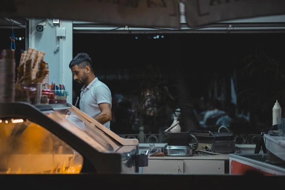 A man working behind the counter of an ice cream shop at night.