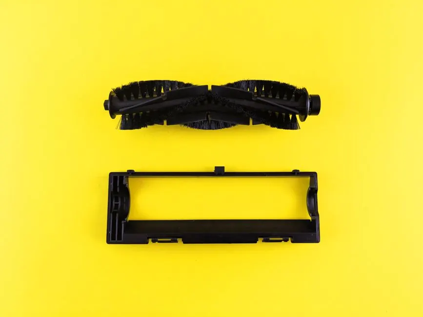 Close-up of vacuum cleaner components on vibrant yellow surface.