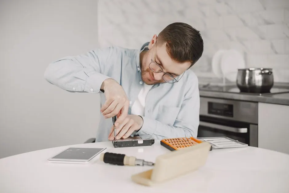 Man wearing glasses using a screwdriver to fix a device.