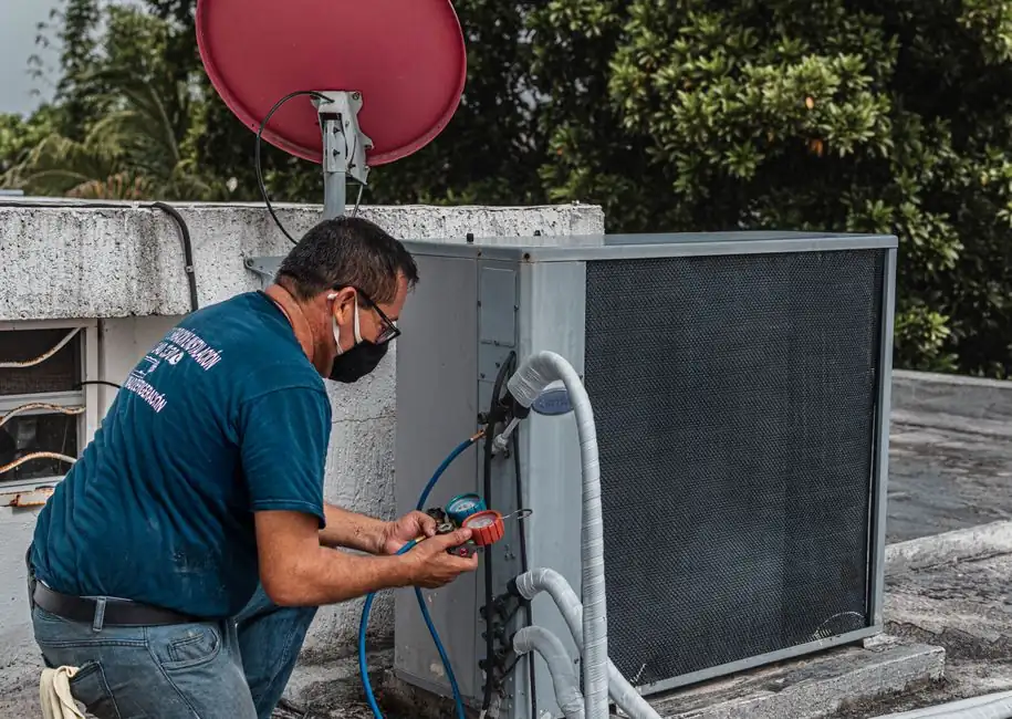 Technician repairing an air conditioner unit outdoors.