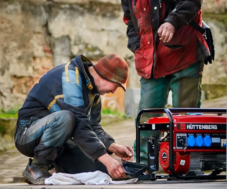 Two technicians working on a power generator outdoors.
